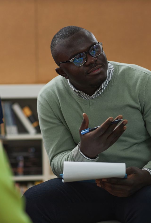 A man holding a pad of paper talks to a small group of teen girls