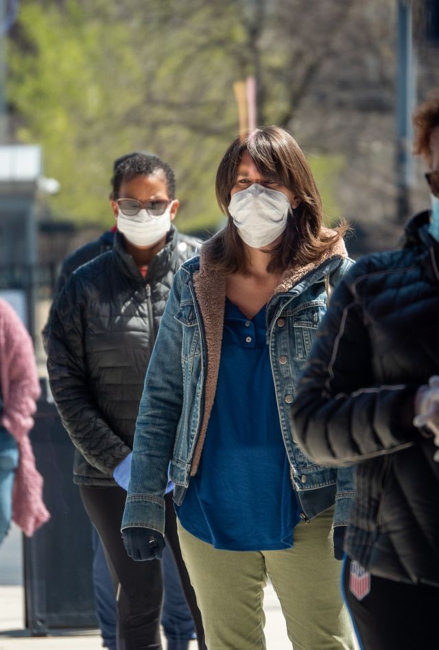 People wearing protective masks wait in line outside to pick up donated PPE on a crisp afternoon in the wake of the Coronavirus COVID-19 pandemic.