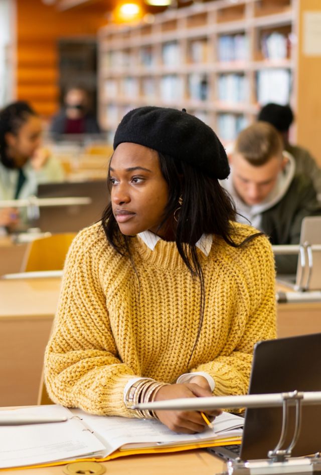 A bored female student is looking towards the window during a class at university