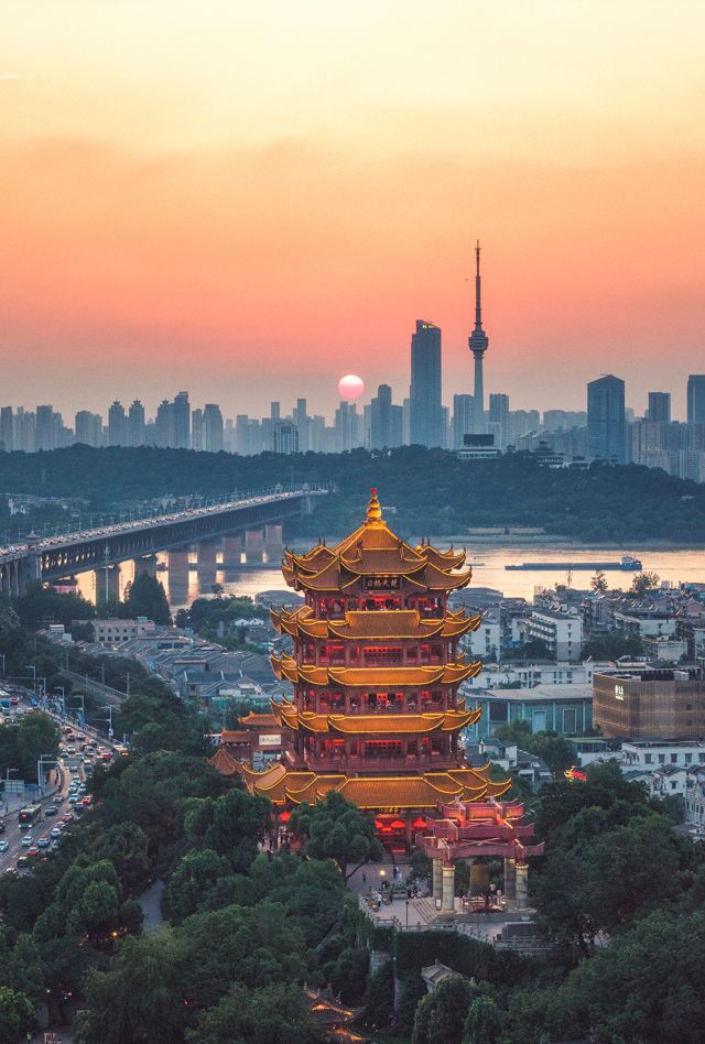 This drone photo was captured on June 13, 2025, near the Yellow Crane Tower Scenic Area in Wuhan. It showcases the renowned Yellow Crane Tower in Wuhan, the cityscape of Wuhan, and the Wuhan Yangtze River Bridge. In the photo, the sunset is in progress, and the sun can be seen setting in the direction of the Guishan TV Tower.