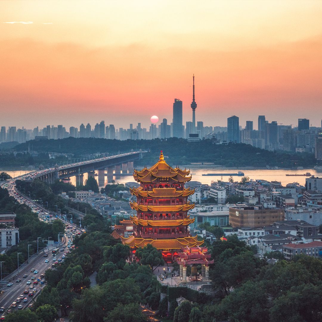 This drone photo was captured on June 13, 2025, near the Yellow Crane Tower Scenic Area in Wuhan. It showcases the renowned Yellow Crane Tower in Wuhan, the cityscape of Wuhan, and the Wuhan Yangtze River Bridge. In the photo, the sunset is in progress, and the sun can be seen setting in the direction of the Guishan TV Tower.