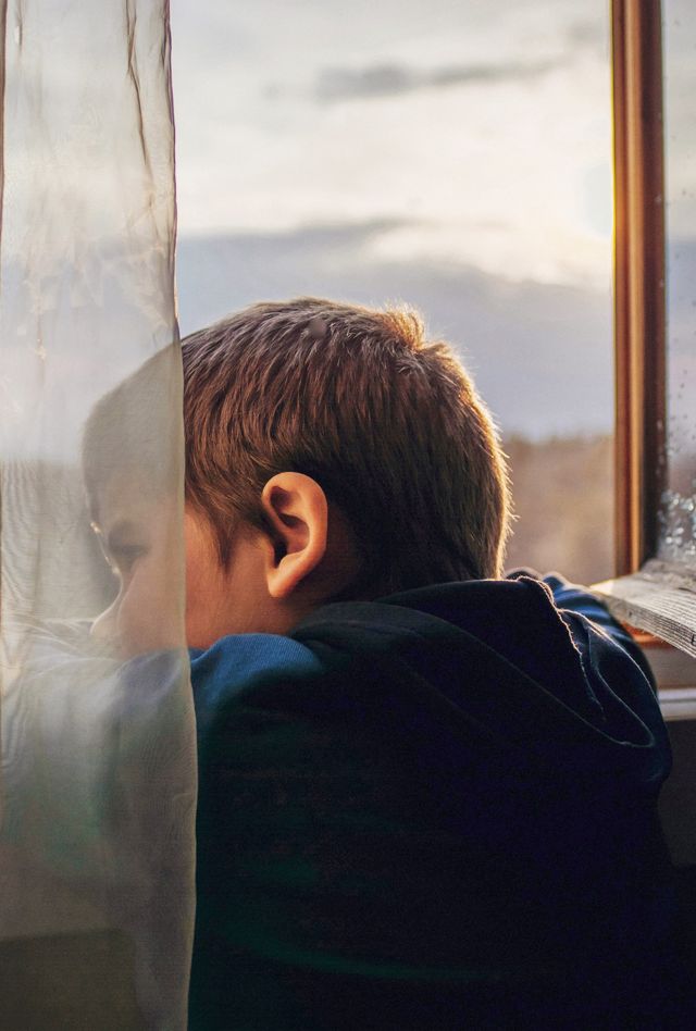 A young boy looks out a window
