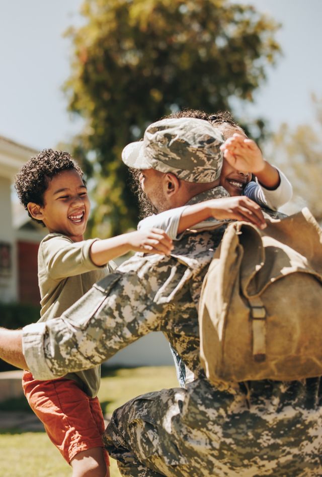 Military dad reuniting with his family at home. American soldier embracing his children after coming back home from the army. Serviceman receiving a warm welcome from his family.