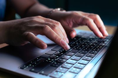 This photo features the hands of a skilled hacker or programmer seamlessly working on a laptop, epitomizing focus, skill, and precision in the digital realm. Ideal for conveying concepts of cybersecurity