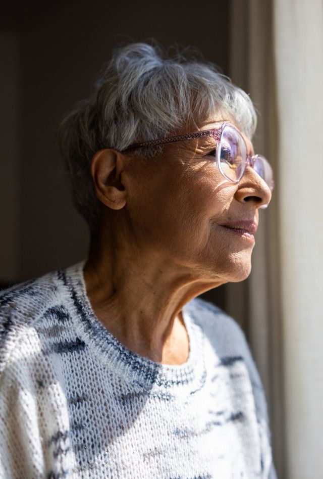 An older woman looks out a window