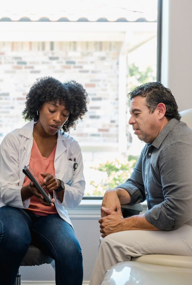 A doctor points out something on her digital tablet to a patient during an exam