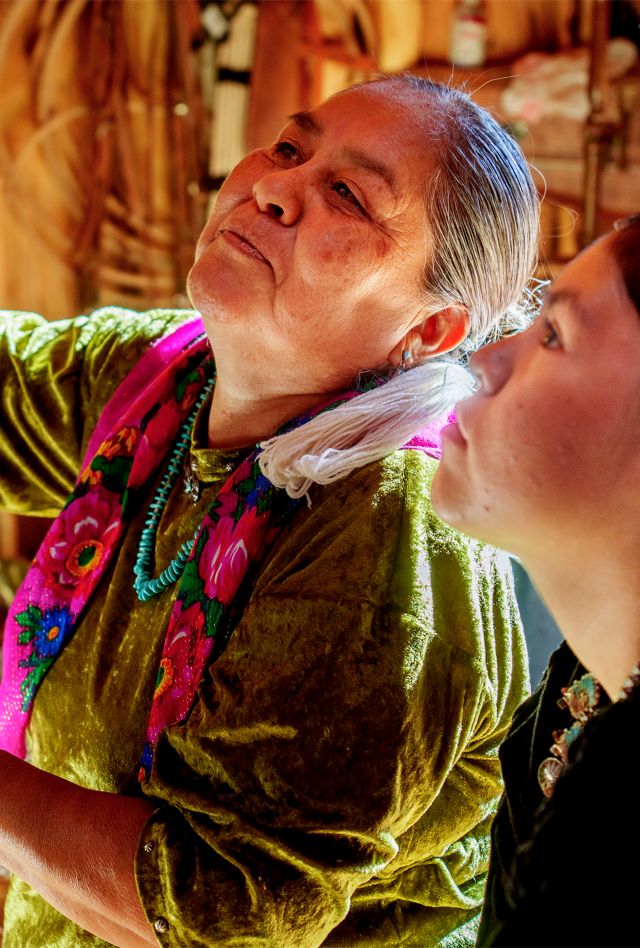 A Navajo grandmother teaching her teenage granddaughter how to weave on a loom