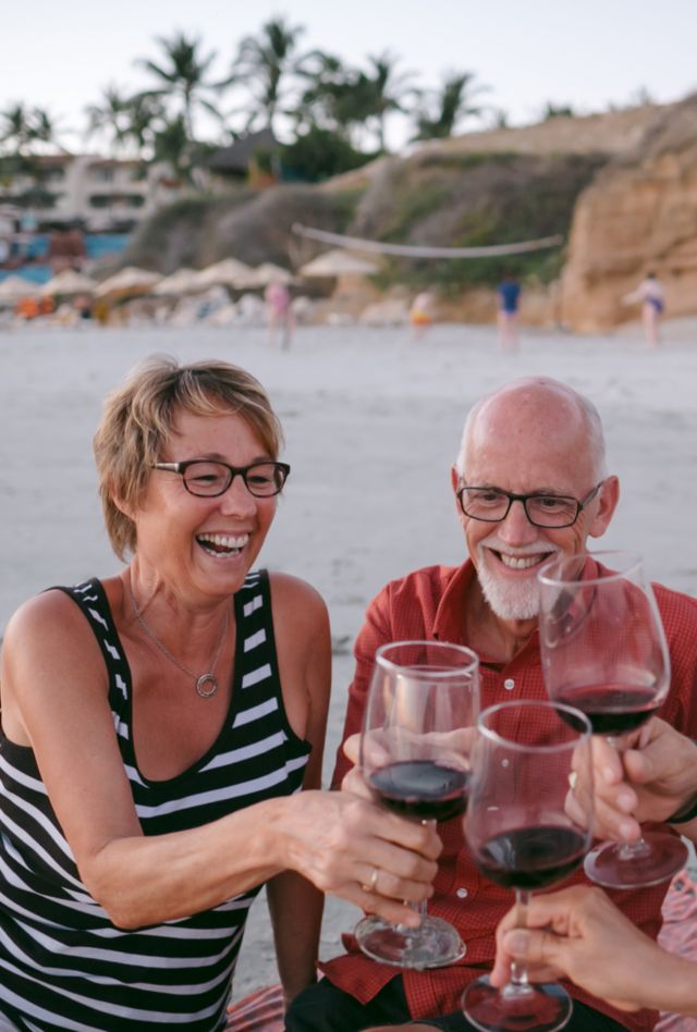 Foursome of mature firiends spending quality time together on warm vacation beach. These beautiful boomers are realxed and enjoying a wine glass toast.