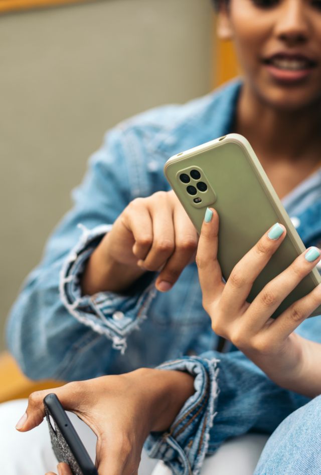 Close up of young latin women looking at smartphone sitting on some stairs in the city