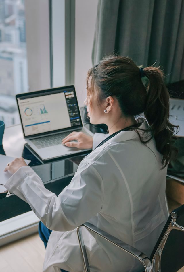 female doctor working on medical report with laptop and document file
