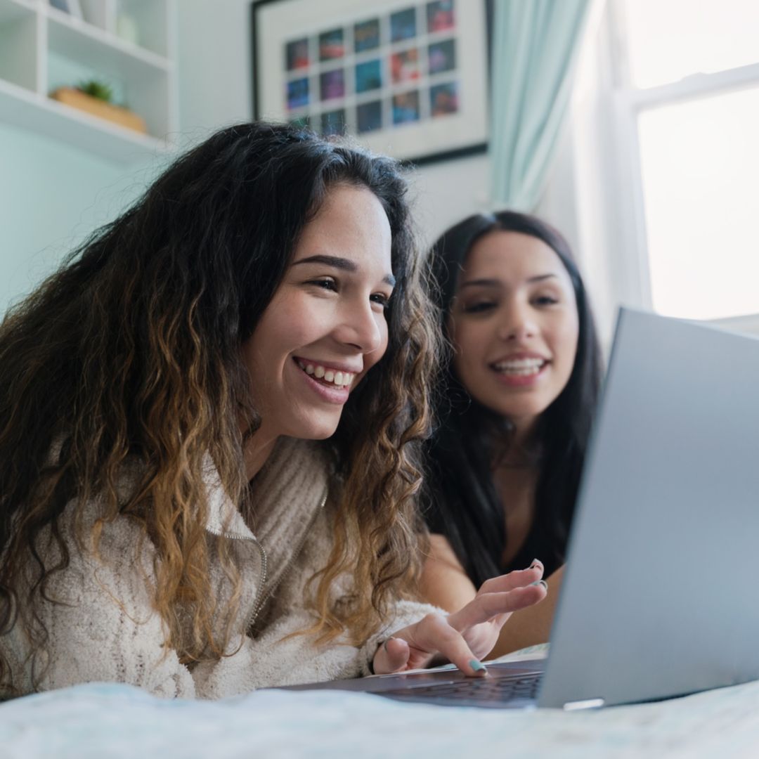 sisters watching shows on a laptop together in their bedroom
