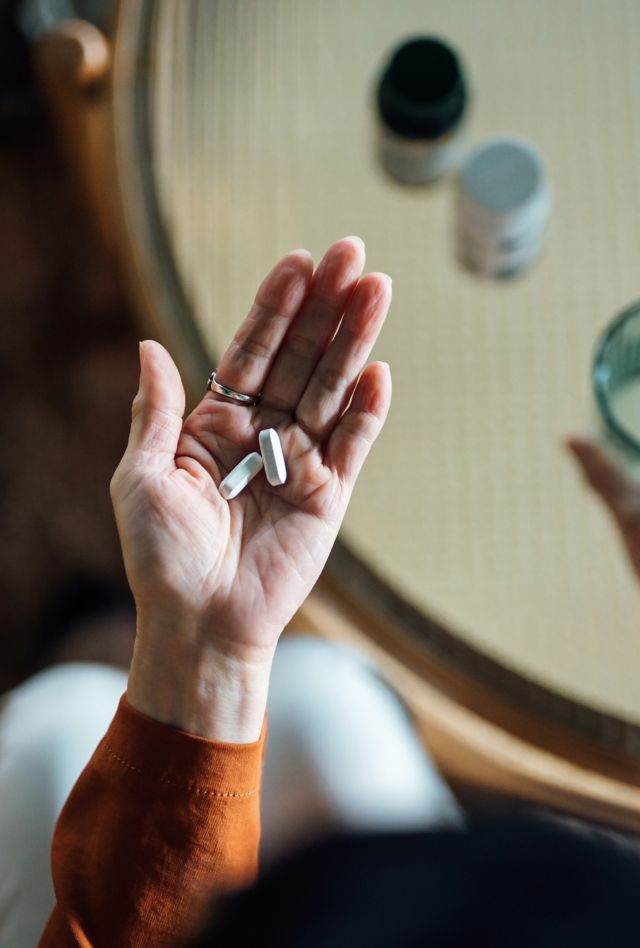 Overhead view of a person taking medicines in hand with a glass of water