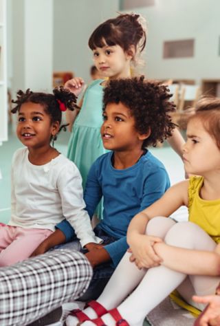 Teacher is playing with cheerful children at kindergarten