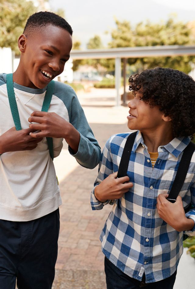 Four middle school kids with backpacks talking as they walk to school