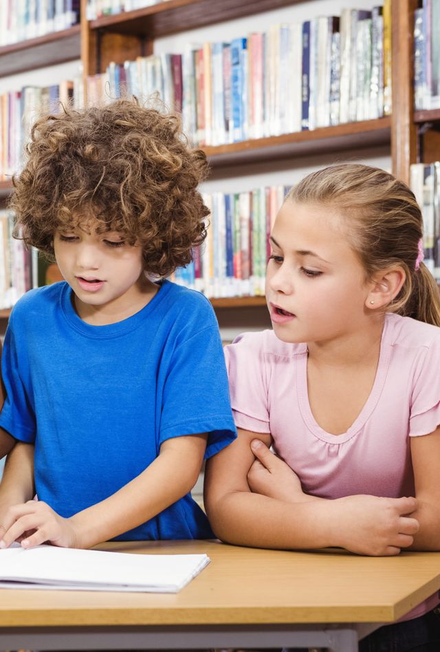 Four elementary age children looking at a book in a library