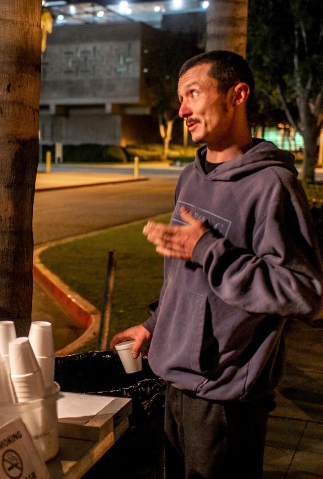 T9738B A bearded volunteer helps a released prisoner with food and support from a van parked outside a county jail at night in Santa Ana, CA.