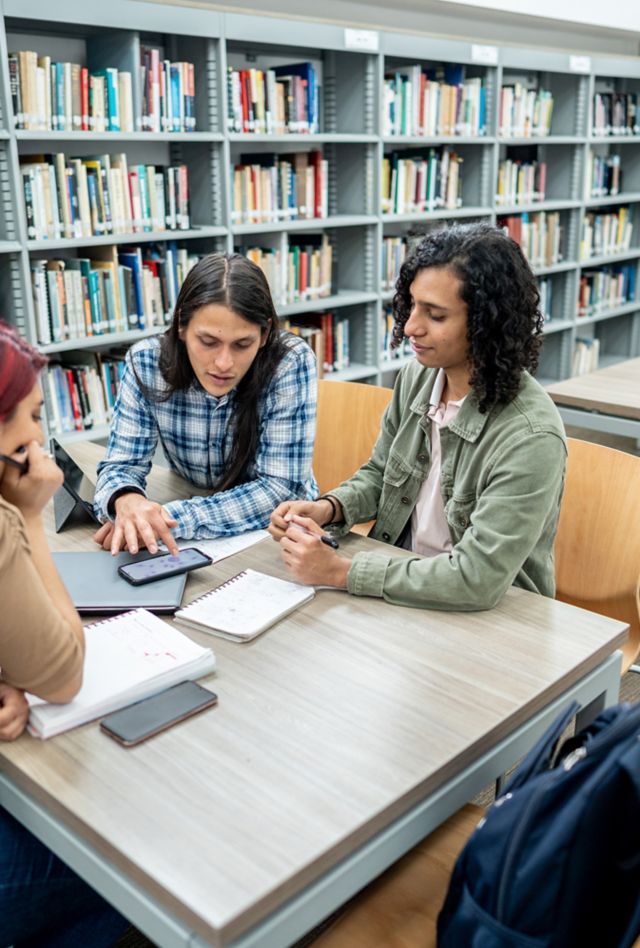 Three people studying in a table in a library