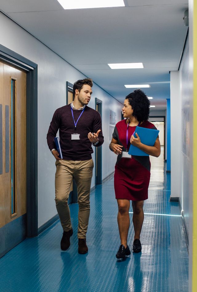 Two teachers talk as they walk down a school hallway