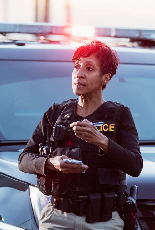 A policewoman taking a statement from a civilian outside her patrol car