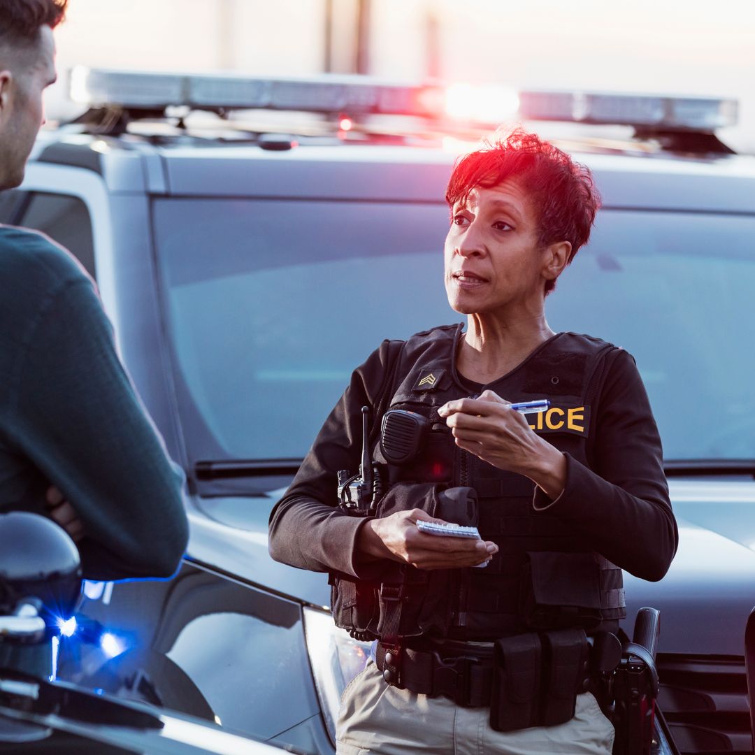 A policewoman taking a statement from a civilian outside her patrol car