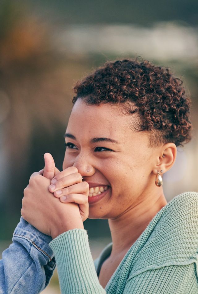 Two young adults clasping hands as they look at each other and laugh