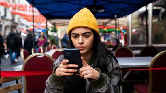 Person using smartphone at restaurant terrace.