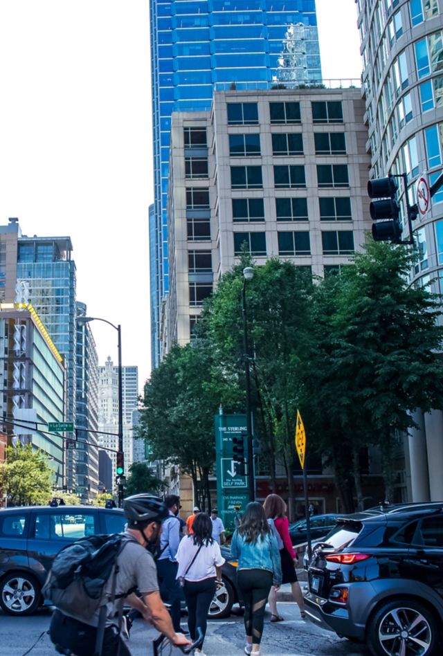 Bicyclists and pedestrians maneuver among traffic on a busy city street