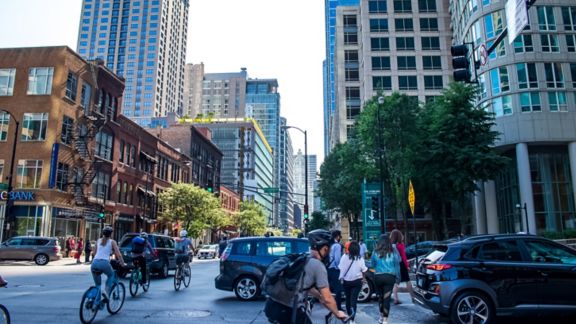 Bicyclists and pedestrians maneuver among traffic on a busy city street