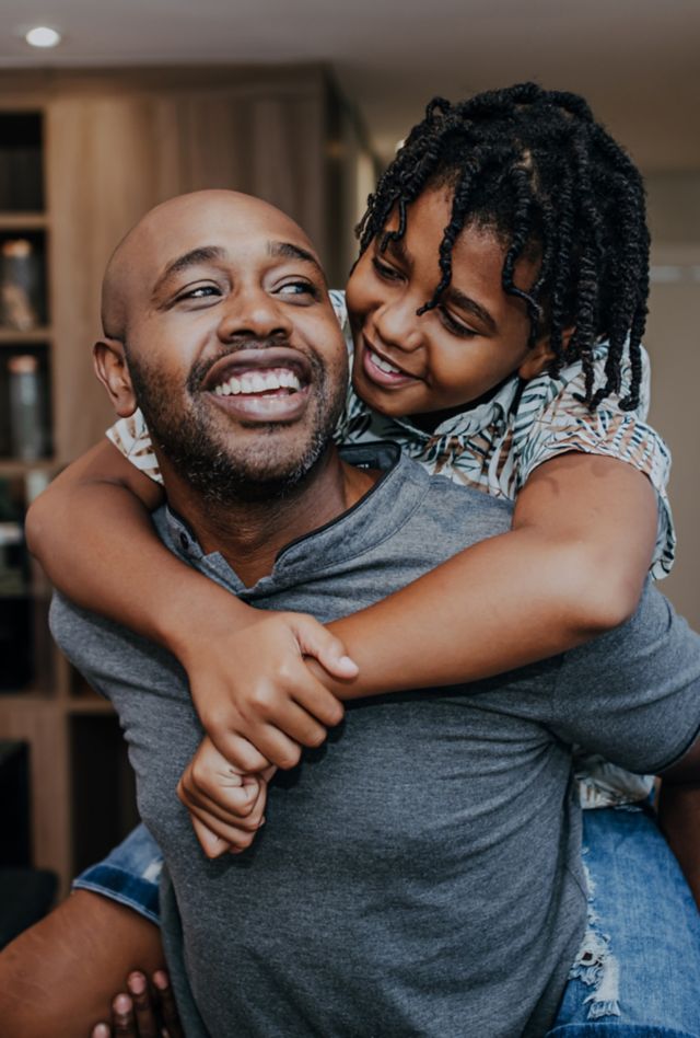 Smiling man carrying young boy on shoulders