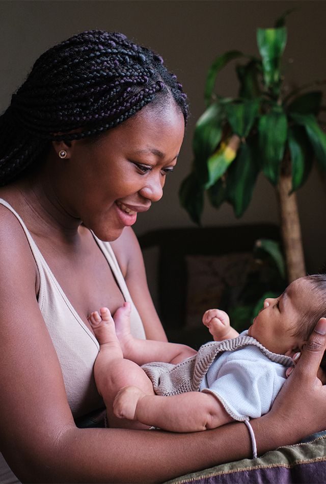 Profile portrait of a happy african mother with her baby on arms at home