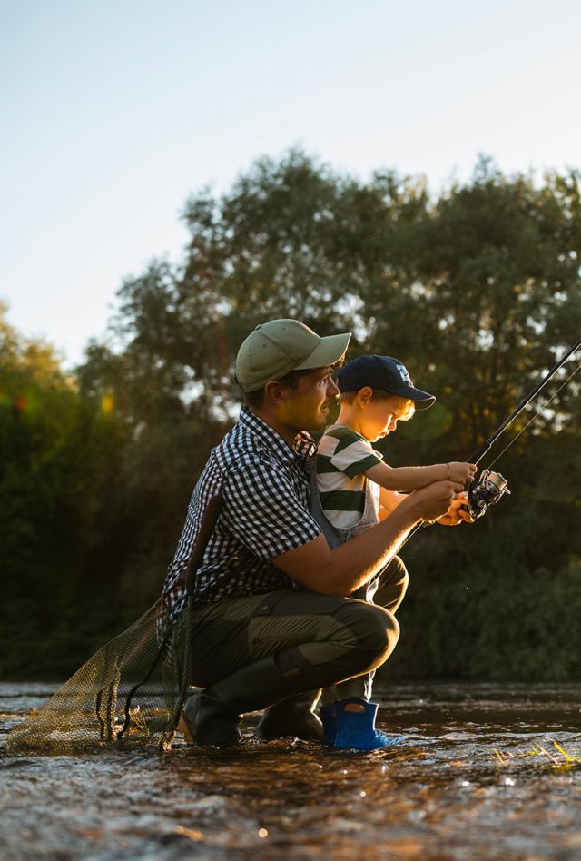 Father and young son enjoying a day by the river, learning, fishing, and creating meaningful memories together.