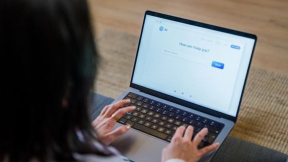 Person using laptop computer interacting with an artificial intelligence chatbot