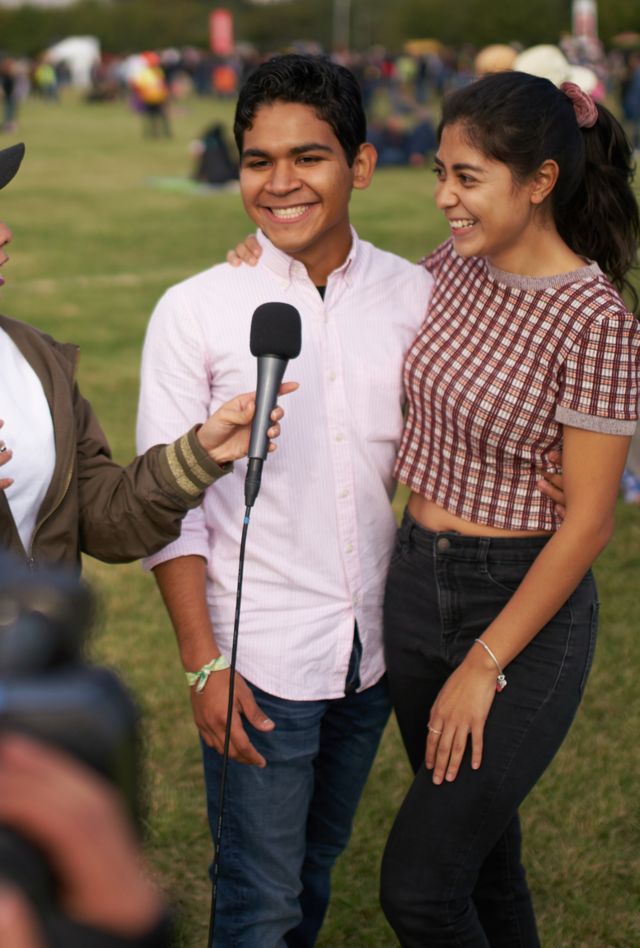 Journalist doing tv interview of couple in front of video camera