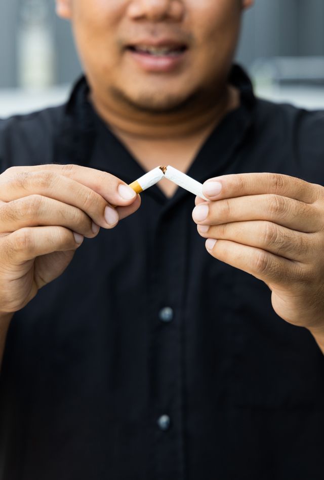 The young man used his hand to break a cigarette into two. He wants to quit smoking for good health. world tobacco day.