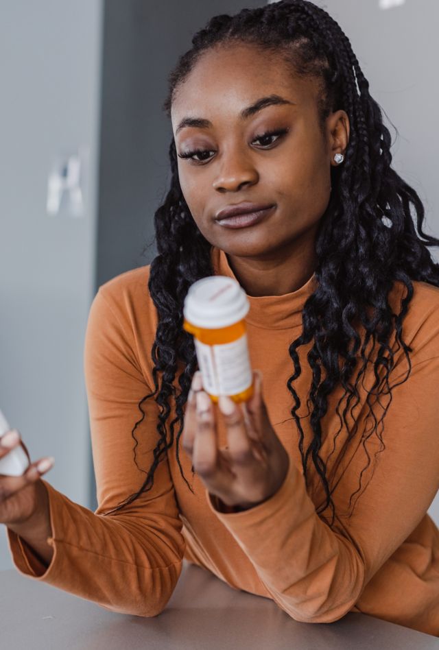 A woman holding a smartphone and a prescription pill bottle