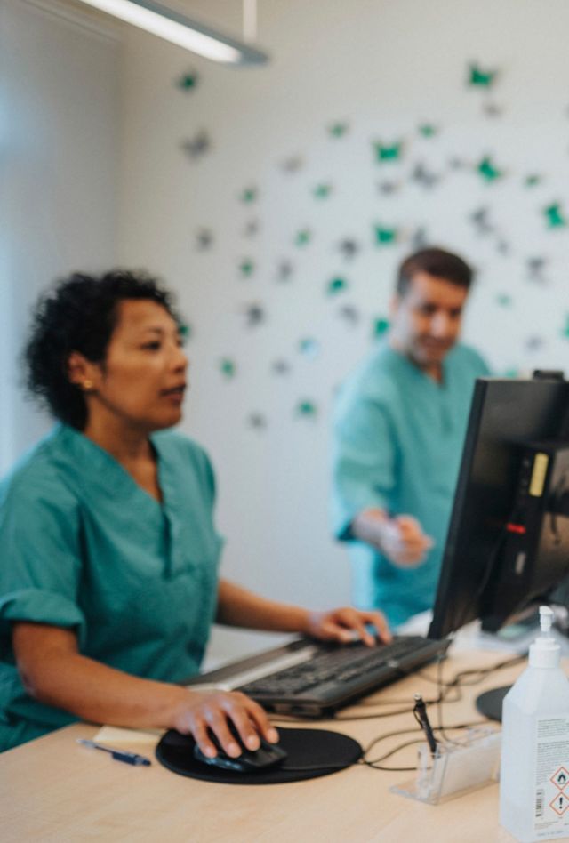 A woman holding a child as she checks in at the front desk of a doctor's office