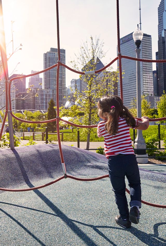 Little girl playing at playground with Chicago's financial district in the background.