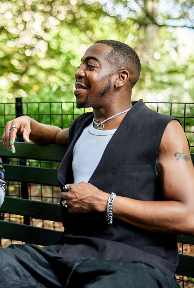 Two young black man sitting on a park bench talking and laughing