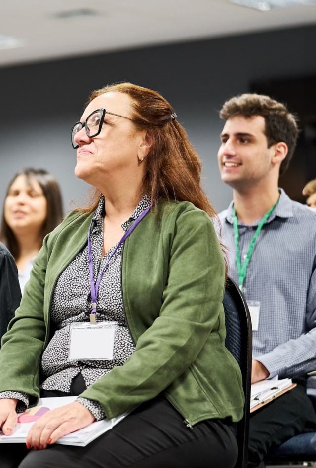 A seated group of people listen to a speaker