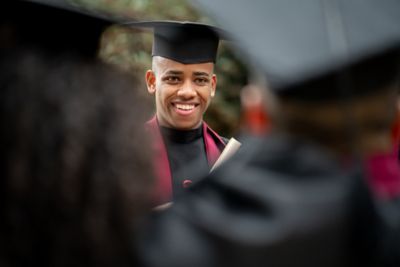 African American student looking happy on his graduation day with a group of friends - education concepts