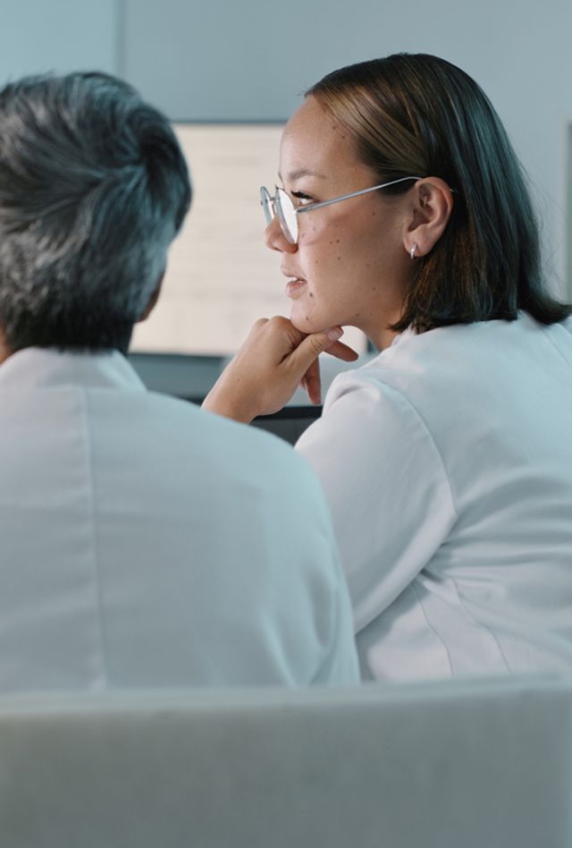 Two people with lab coats working at a computer