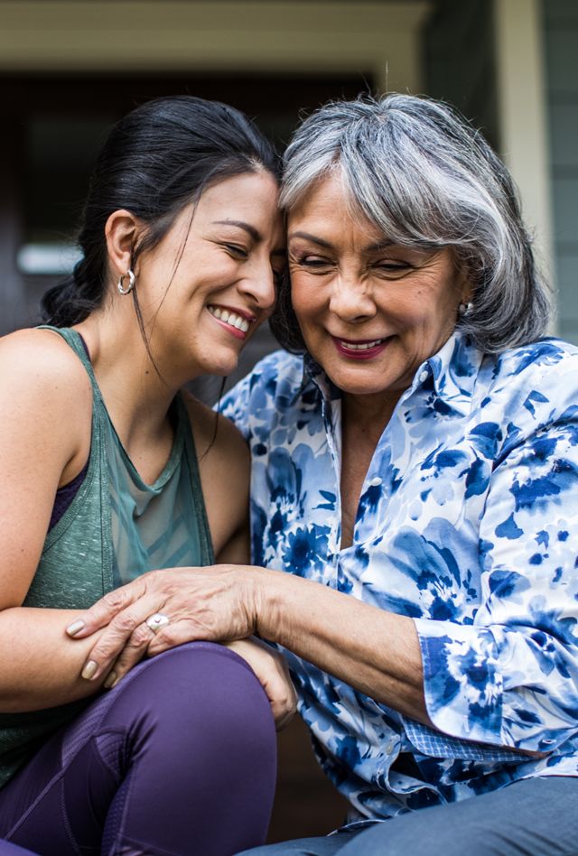 Older adult woman and adult daughter laughing on porch