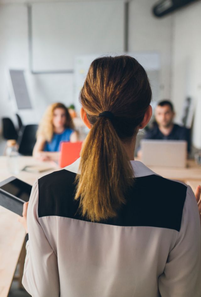 Woman presenting in fornt of a group of business people.