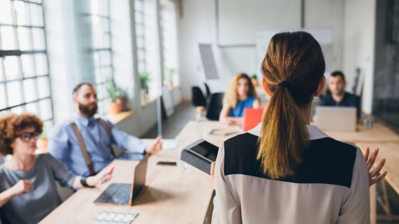 Woman presenting in fornt of a group of business people.