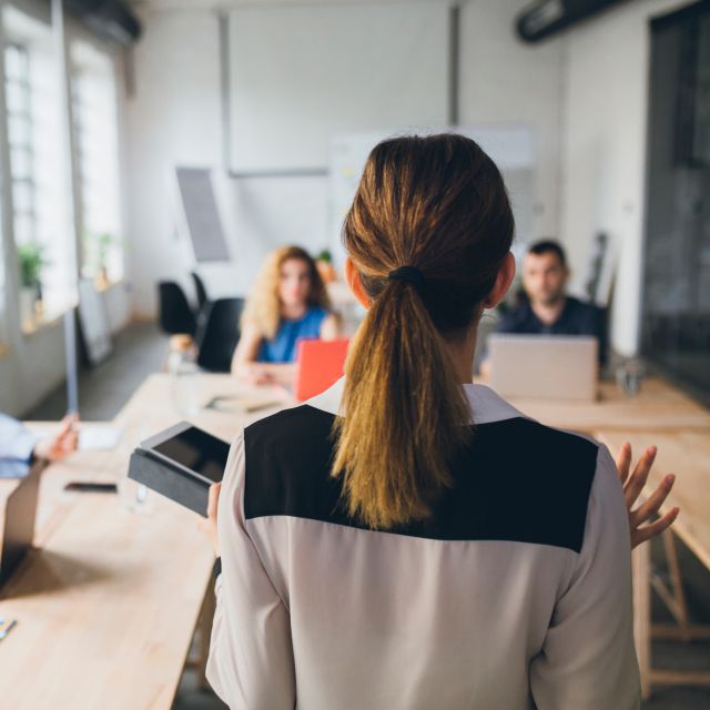 Woman presenting in fornt of a group of business people.