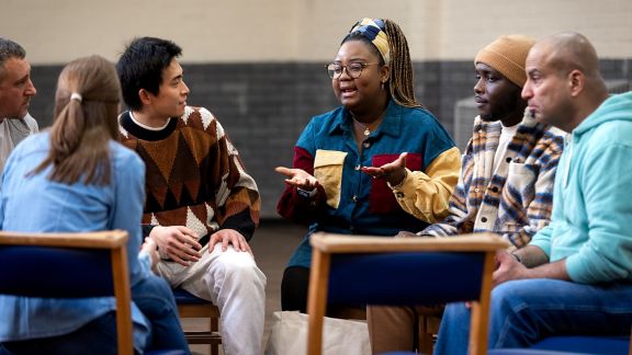 A group of adults of sitting in a circle and talking