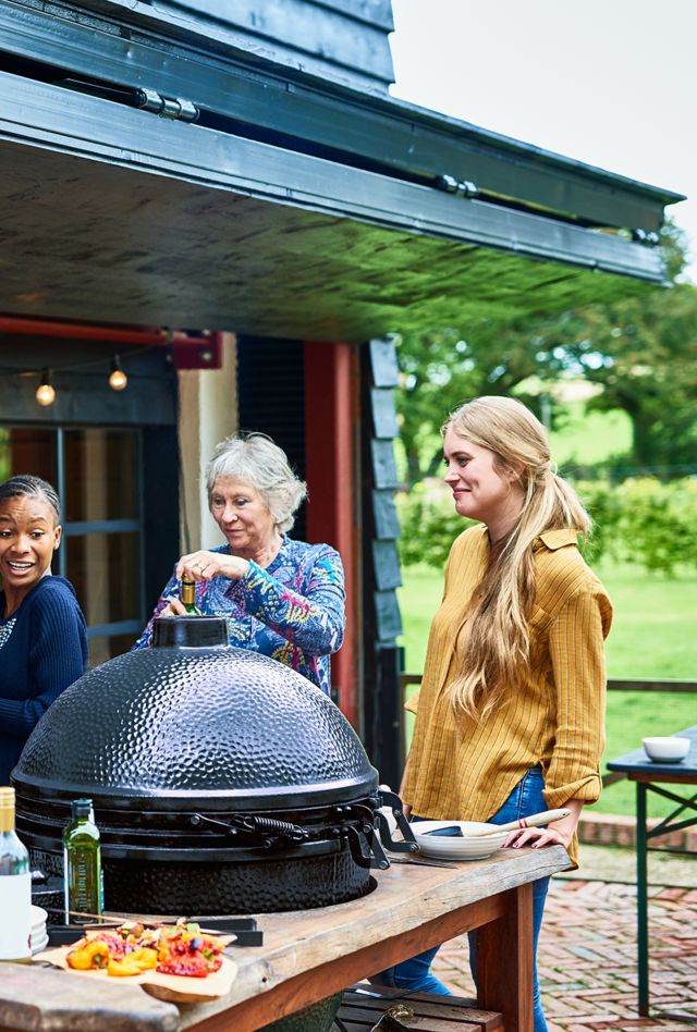People of different ages and races preparing a barbecue on the deck of a home