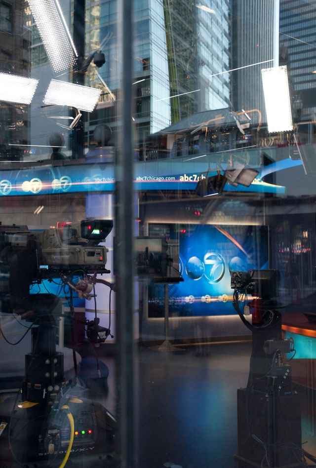 Wide view of a television news studio as the anchors prepare for broadcast.
