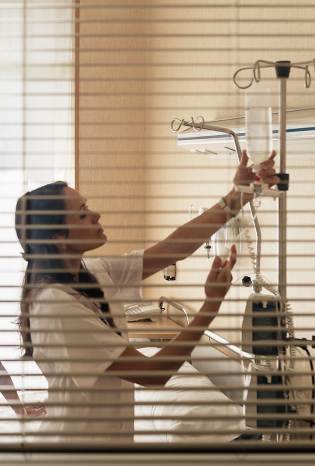 Patient being evaluated in bed by doctor while nurse is checking the medical equipment