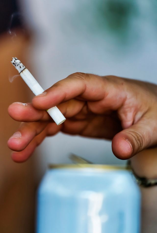 Close-up of someone holding a lit cigarette